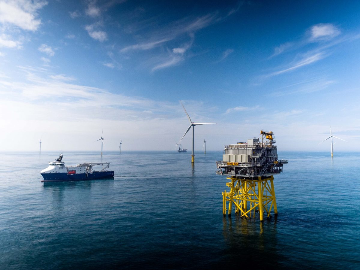 Offshore wind farm setting with a substation, several wind turbines, and an offshore support vessel