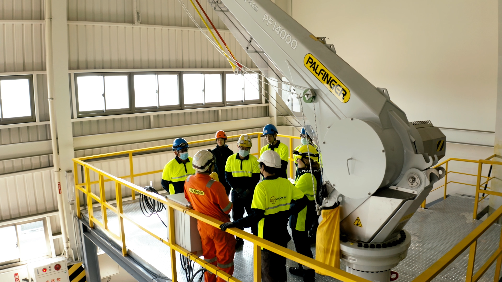 Eight people during an operator training standing in a circle next to a crane.