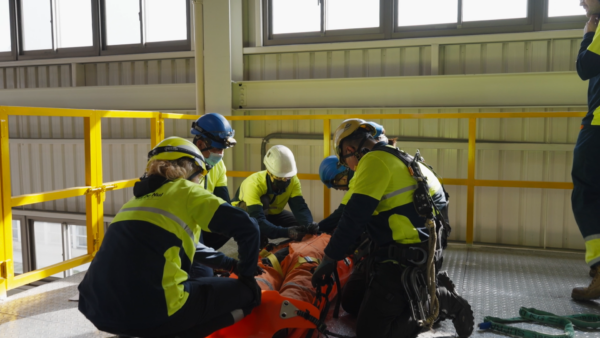 Five people simulating first aid procedures as part of a crane operator training.