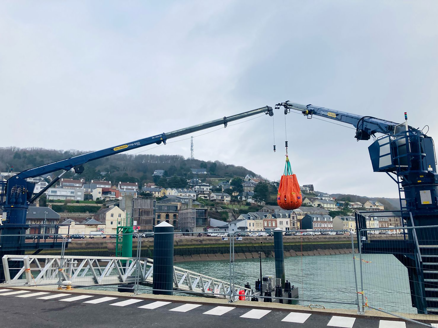 Two blue PALFINGER MARINE cranes installed at an operation and maintenance base, / the harbour of an offshore wind farm.